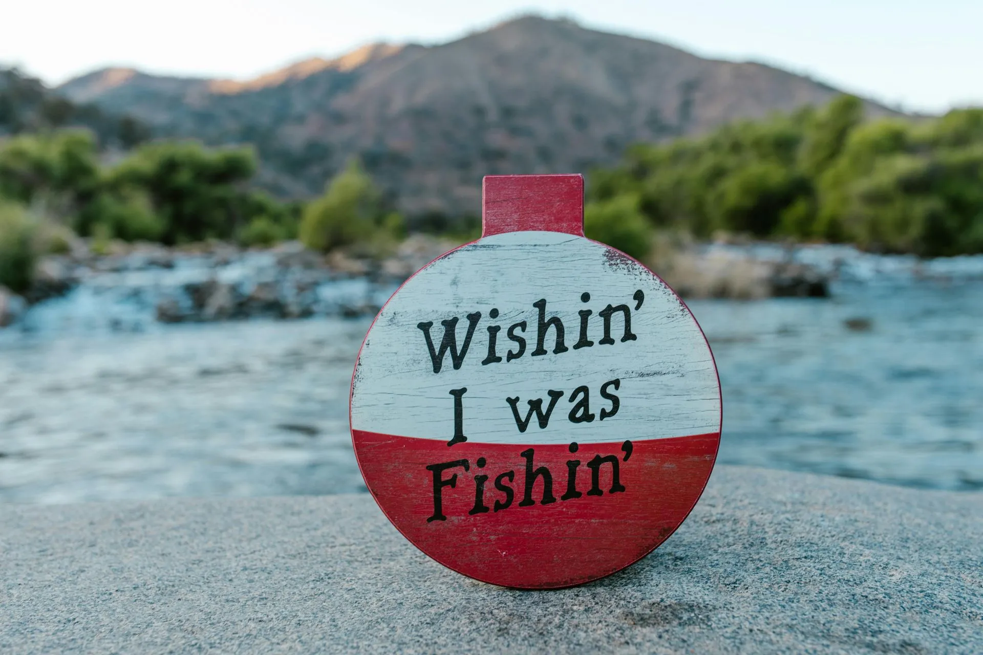 Fishing sign beside the water with mountains beyond