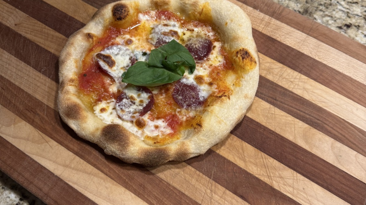 Sourdough pizza cooking on a smoky charcoal grill